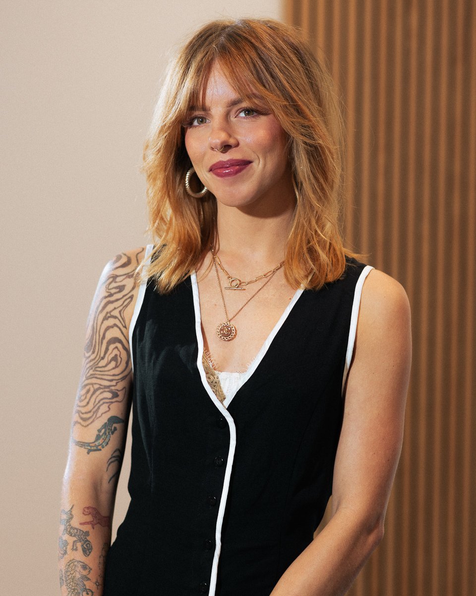 Raegen Blade, blonding specialist with lived‑in colour and balayage, smiling with tattooed arm.