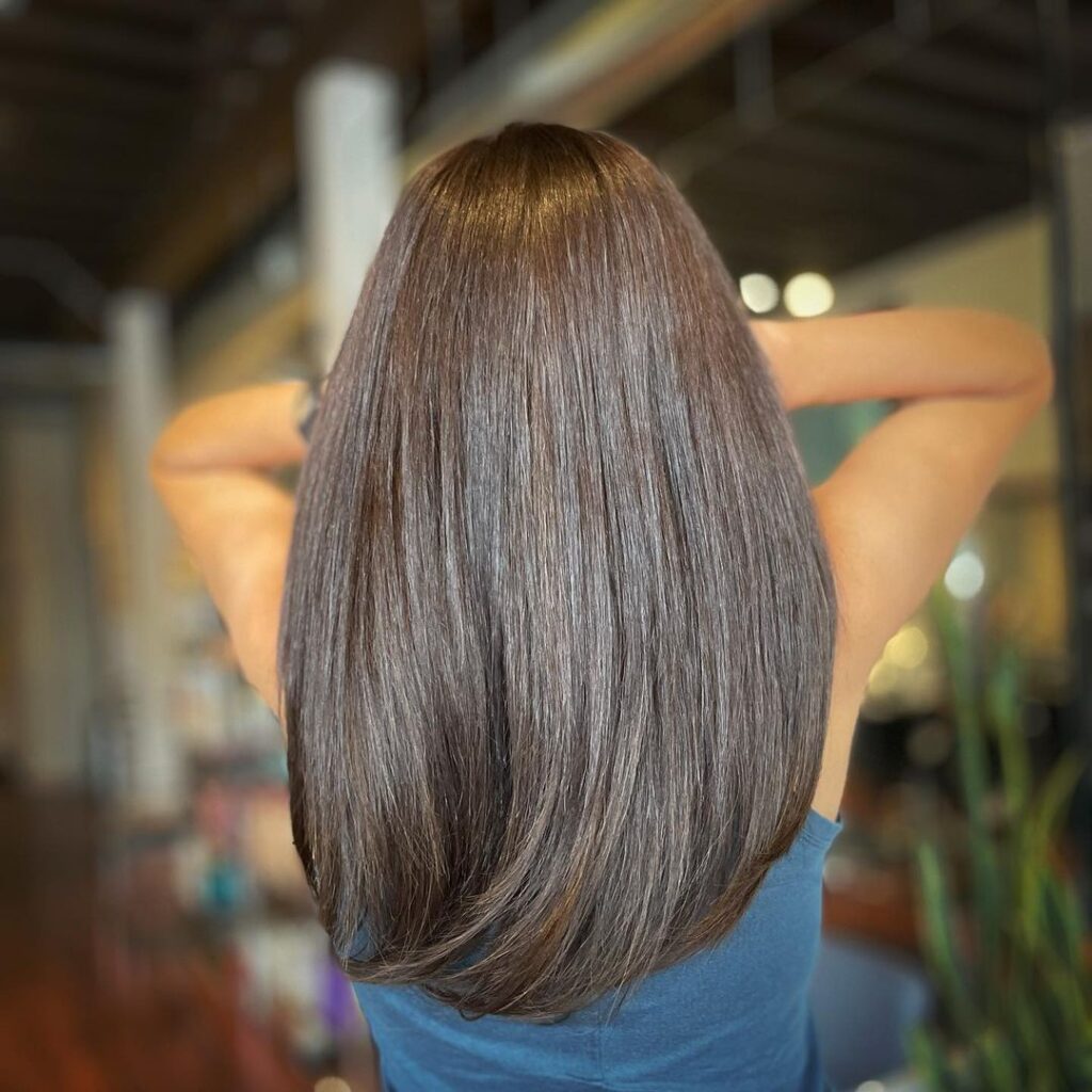 Back view of long dark hair after a keratin smoothing treatment, showing sleek, frizz-free, and shiny locks.
